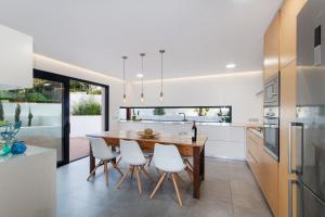 a kitchen with a wooden table and white chairs at Villa O2 Mallorca - by EMERALD STAY in Cielo de Bonaire 