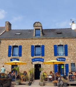a brick building with umbrellas and people sitting outside at Les Ganivelles in Belz