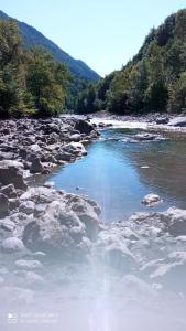 a river with rocks and blue water and trees at Chambre avec lit 2 personnes in Ville-en-Sallaz