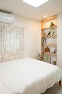 Un dormitorio con una cama blanca y una ventana. en Cream HOUSE, en Busan