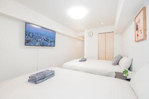 two beds in a room with a tv on the wall at 新宿市中心歌舞伎客房源出行便利免费Wi-Fi in Tokyo