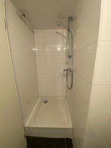 eine Dusche in einem weiß gefliesten Bad in der Unterkunft Kleever Apartment Bad Schwalbach in Bad Schwalbach