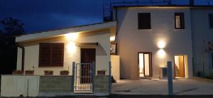 een wit huis met 's nachts een poort ervoor bij TuscanyAnnerelax in Cecina
