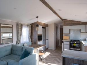 a living room with a blue couch and a kitchen at Pinewoods Park Classic no.1 - sleeps 6 – no dogs in Wells next the Sea