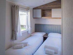three beds in a room with a window at Pinewoods Park Classic 5 sleeps 6 – dog friendly in Wells next the Sea