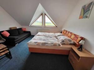 a bedroom with a bed and a couch and a window at Penzion Náš svět in Pržno