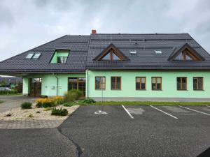 a green building with a black roof and a parking lot at Penzion Náš svět in Pržno
