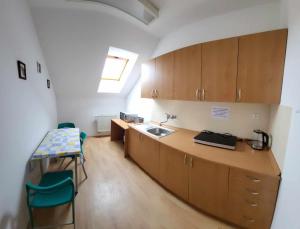 a kitchen with wooden cabinets and a sink and a table at Penzion Náš svět in Pržno