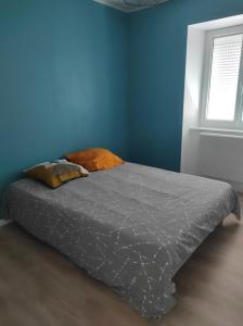 a bed in a bedroom with a blue wall at Appartement à la campagne in Venteuges
