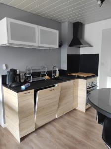 a kitchen with wooden cabinets and a black counter top at Appartement à la campagne in Venteuges +5 photos