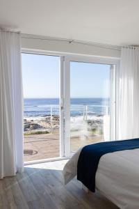 a bedroom with a bed and a view of the ocean at Shades of Blue in St Helena Bay