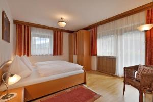 1 dormitorio con 1 cama, 1 silla y ventanas en Apartment Alpin, en Aschau