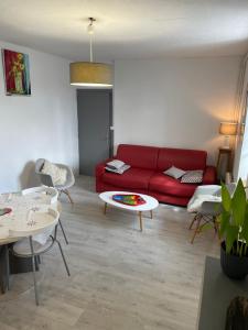 a living room with a red couch and a table at Gîte en bord de lac in Monsireigne