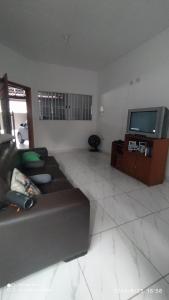 a living room with a couch and a tv at Casa cachoeira dos tourinhos in Massaguassu