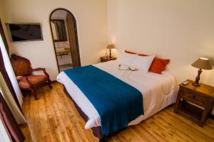 a bedroom with a bed and a chair and a mirror at Hotel Spa Mansion Santa Isabella in Riobamba