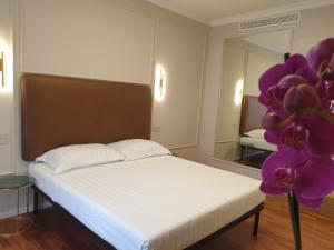 罗马Appian Private Suites的一间卧室配有一张床、镜子和紫色的鲜花