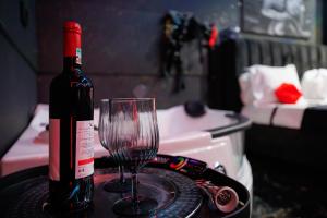 a bottle of wine and a glass on a table at Romeo Nights - Private Rooms - Adults Only in Bucharest