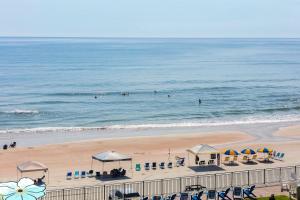 een strand met parasols en mensen in het water bij "SHERWIN" Coastal Vibes Oceanfront Condominium 301 in Daytona Beach