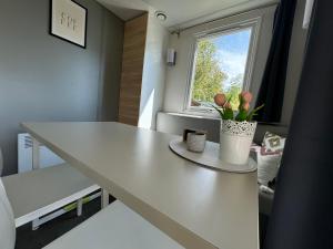 una camera con un tavolo bianco e una finestra di Low Budget - 4 persoons chalet aan het Lauwersmeer a Lauwersoog