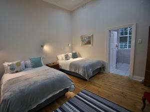 a bedroom with two beds and a door to a bathroom at Lilibet Lodge in Graaff-Reinet