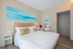 阿纳卡普里Five by Capri 5 Senses的卧室配有一张白色床,墙上挂有绘画作品