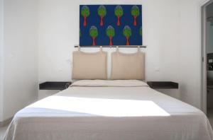 カストロ・ディ・レッチェにあるAppartamento Argentieraの白いベッド1台付きのベッドルーム1室(壁に絵画付)