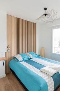 a bedroom with a large bed with blue sheets and a fan at T2 parking gratuit plus 2 balcons in Aix-les-Bains