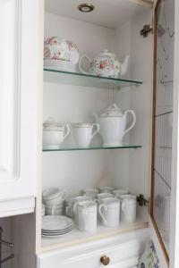 a cupboard filled with white cups and teapots at 3 bed home sleeps 8 people located 1 min from train stop - Otley Terrace in Oldham
