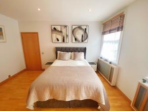 a bedroom with a large bed and two windows at Luxury Belgrave Square Private Mews TownHouse in London