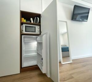 a refrigerator with a microwave and a television in a room at Paralelos Moledo Beach Suite in Moledo