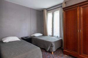 a bedroom with two beds and a window and a dresser at Grand Hôtel De Paris in Paris