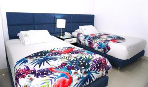 a hotel room with two beds with colorful blankets at Hotel Bolivariana Plaza Medellin in Medellín