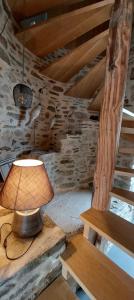 a lamp sitting on a table next to a stone wall at Les Grands Gîtes de Cancale, gîtes de charme avec jacuzzi in La Coudre