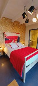 a bedroom with a large bed with a red blanket at Les Grands Gîtes de Cancale, gîtes de charme avec jacuzzi in La Coudre
