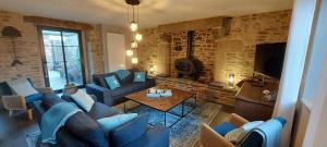 a living room with blue couches and a tv at Les Grands Gîtes de Cancale, gîtes de charme avec jacuzzi in La Coudre