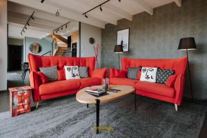 a living room with two red couches and a table at Les Grands Gîtes de Cancale, gîtes de charme avec jacuzzi in La Coudre
