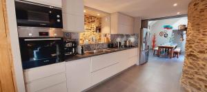 a kitchen with white cabinets and a large appliance at Les Grands Gîtes de Cancale, gîtes de charme avec jacuzzi in La Coudre