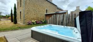 a hot tub sitting on a deck next to a building at Les Grands Gîtes de Cancale, gîtes de charme avec jacuzzi in La Coudre