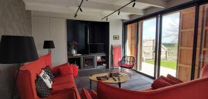 a living room with red chairs and a table at Les Grands Gîtes de Cancale, gîtes de charme avec jacuzzi in La Coudre