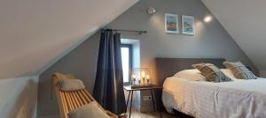 a bedroom with a bed and a chair and a window at Les Grands Gîtes de Cancale, gîtes de charme avec jacuzzi in La Coudre