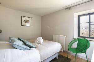 a bedroom with a bed and a green chair at Les Grands Gîtes de Cancale, gîtes de charme avec jacuzzi in La Coudre