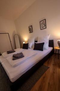 a large bed with white sheets and black pillows at Stilvoll, Innenstadt, Parken in Hameln +9 photos