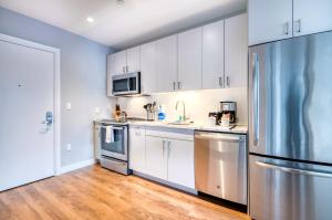 Una cocina con gabinetes blancos y un refrigerador de acero inoxidable. en Modern Apt with Water Views, en Boston