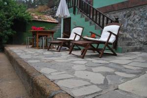 three chairs and a table on a stone patio at Finca Rural El Silbo - Casas Rurales in Hermigua