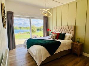 a bedroom with a large bed with a large window at Phoenix Lodge - Luxury 2 ensuite bedrooms, lakeside views in Newark upon Trent