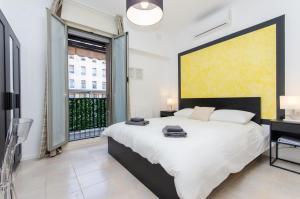 une chambre avec un grand lit et une grande fenêtre dans l'établissement Yellow Room, à Milan