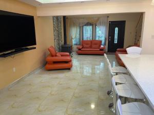 a living room with orange chairs and a flat screen tv at Luxury Pocono Retreat with hot tub, sauna, fire pit, and patio in East Stroudsburg