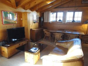 un soggiorno con un divano, una TV e un tavolo di South Facing Family Chalet in Saanen Village a Gstaad