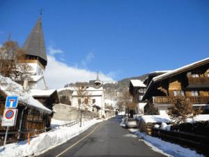 una strada innevata in una città con edifici di South Facing Family Chalet in Saanen Village a Gstaad