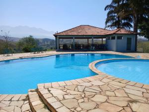 a large swimming pool with a building in the background at Pousada e Espaço Flor da Serra in Cruzeiro